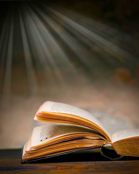 Christian Bible Open Christian bible with light rays streaming downward in background holy book stock pictures, royalty-free photos & images