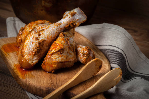 istock Marinated chicken drumsticks on a wooden chopping board. 1048828512