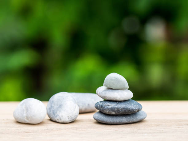 istock Four stones stacked placed on a wooden board. The backdrop is black on green. 1048831284