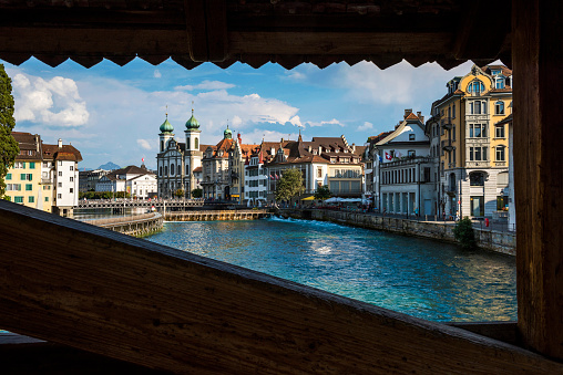 View of the historic Lucerne city landscape from Mill Bridge's window on Reuss River's  with Jesuit Church in Switzerland.