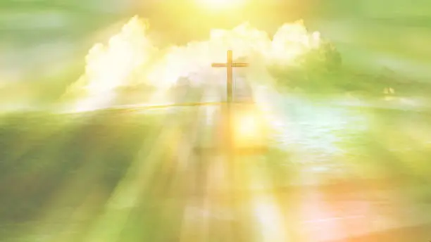Photo of symbol of religious cross on a beach with sunlight ray and cloud