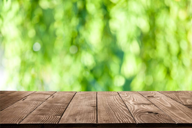 istock Backgrounds: Empty wooden table with green lush foliage at background 1048838362