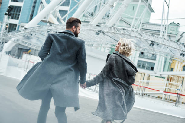 istock Romantic date outdoors. Young couple running at entertainment park holding hands back view looking at each other smiling happy 1048839572