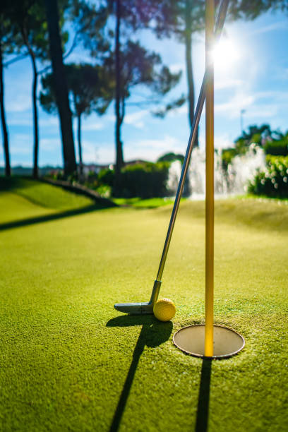 istock Mini Golf yellow ball with a bat near the hole at sunset 1048842796