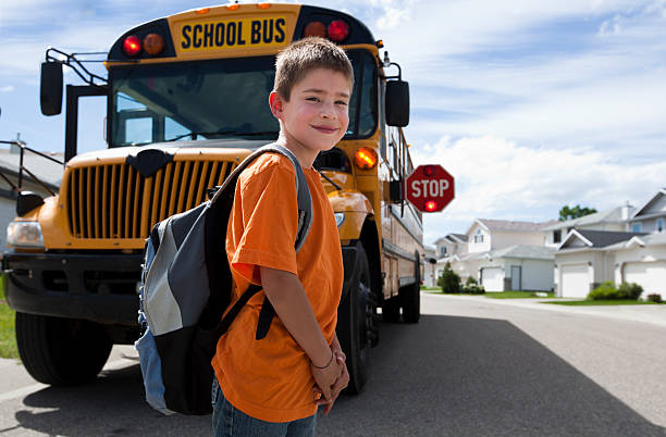 Schoolboy waiting to cross the street after departing bus stock photo
