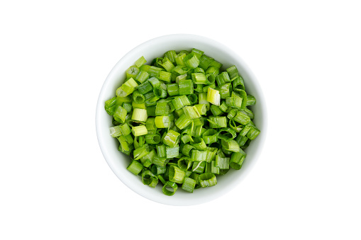 Finely chopped fresh green onions in a generic ceramic ramekin viewed from above isolated on white