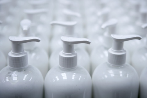 White plastic soap bottles in rows, cosmetics laboratory assembly line