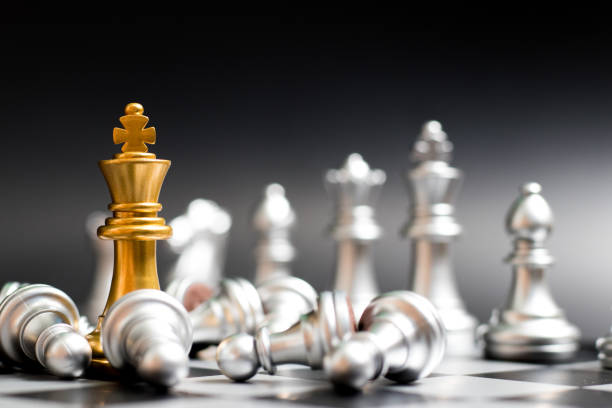 istock Gold king chess piece face with another silver team and have pawn lay down on black background (Concept for company strategy, business victory or decision) 1048867060