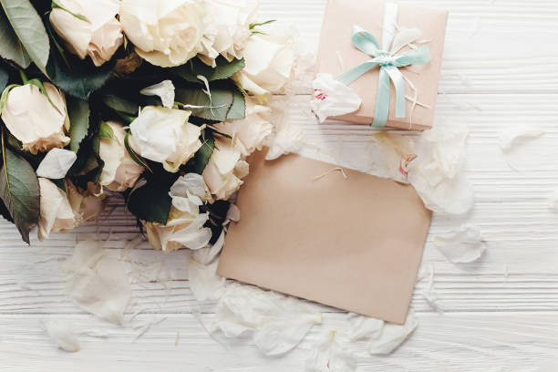 istock White roses with empty card and gift box on wooden background, flat lay with space for text. Floral greeting card mockup. Wedding invitation,happy mother day concept. Valentine day 1048868050