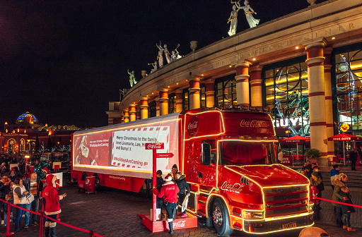Manchester, UK - Coca-Cola's Santa touring truck visiting Manchester, with people preparing to pose for a photo, and a queue of visitors at the left.