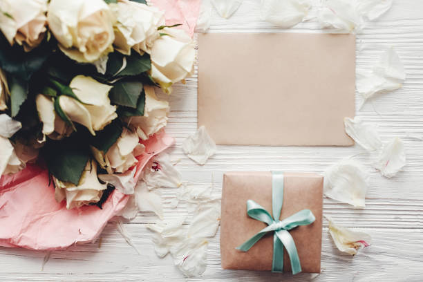 istock White roses with empty card and gift box on wooden background, flat lay with space for text. Floral greeting card mockup. Wedding invitation,happy mother day concept. Valentine day 1048872666