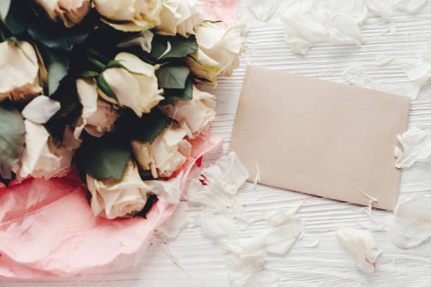 istock White roses with empty card on wooden background, flat lay with space for text. Floral greeting card mockup. Wedding invitation,happy mother day concept. Valentine day 1048872692