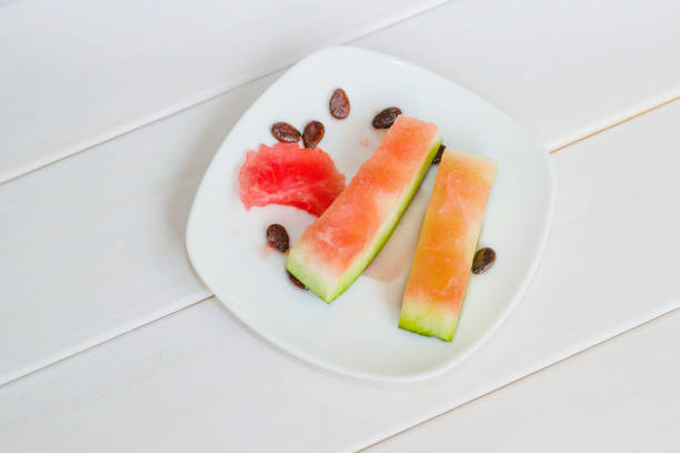 Watermelon peel and seeds on white plate on white wooden table background