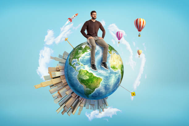 istock A bearded man sits on a small Earth globe with skyscrapers on its surface and hot air balloons flying around. 1048873444