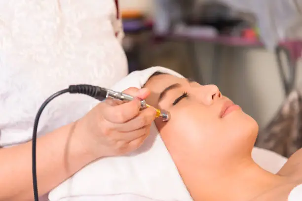 Photo of Rejuvenating facial therapy treatment at spa salon clinic. Young beautiful Asian woman getting lifting anti-aging, face massage and skincare by electroporation facial therapy aesthetic cosmetology.Healthy Concept