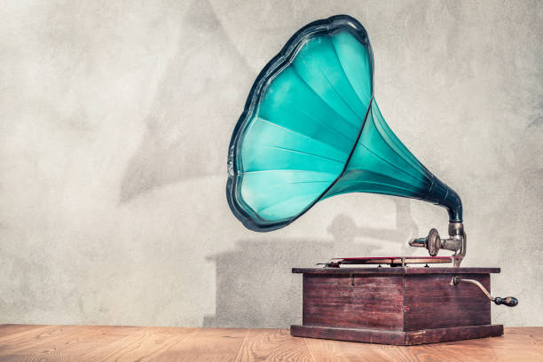 vintage antique aged aquamarine gramophone phonograph turntable on wooden table front concrete wall background with its shadow. retro old style filtered photo - gramophone imagens e fotografias de stock