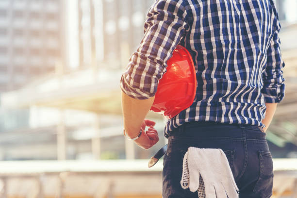 istock Architect worker holding yellow helmet a for workers security control at city site. 1048889534