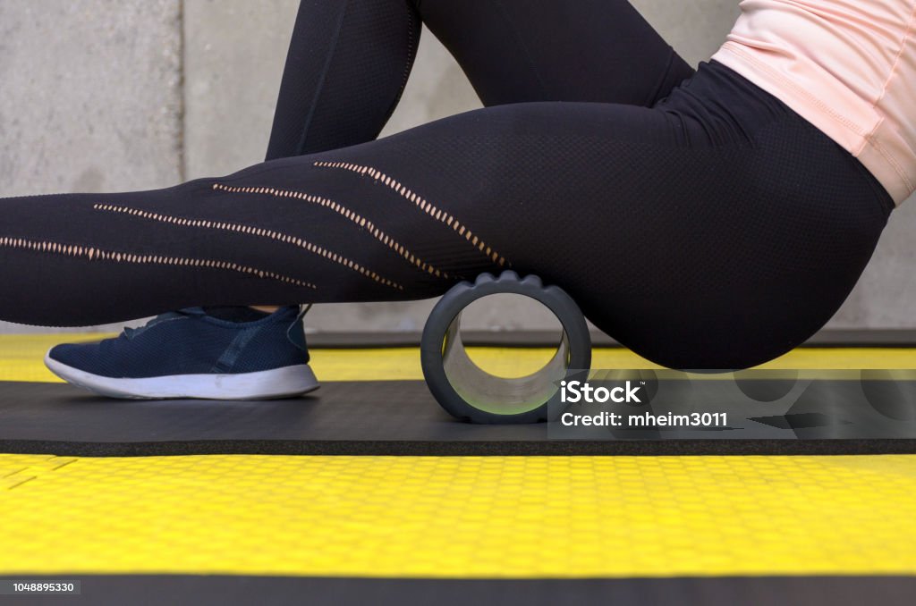Close up view of woman exercising with foam roller Close up view of woman exercising with foam roller at gym Rolling Stock Photo