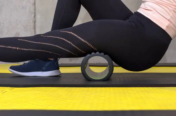 Close up view of woman exercising with foam roller at gym