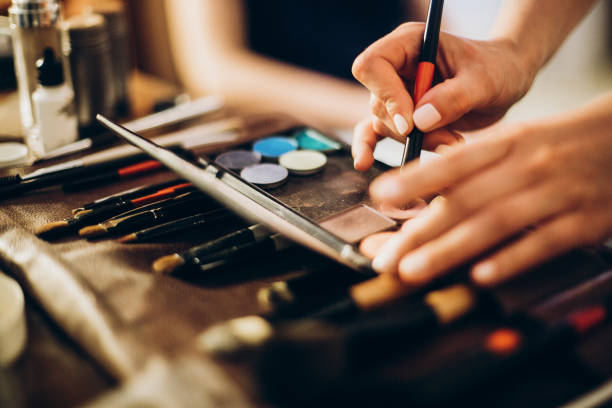istock hands holding brush and eyeshadow palette. makeup artist making gorgeous make-up for bride in the morning. beauty and fashion image. set of brushes, powder, eyeshadows on table 1048912202