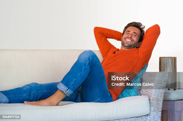 Lifestyle Home Portrait Of Young Attractive And Happy 30s Man Smiling Relaxed And Comfortable Lying At Living Room Sofa Couch In His Modern Apartment Cheerful And Positive In Success Concept Stock Photo - Download Image Now