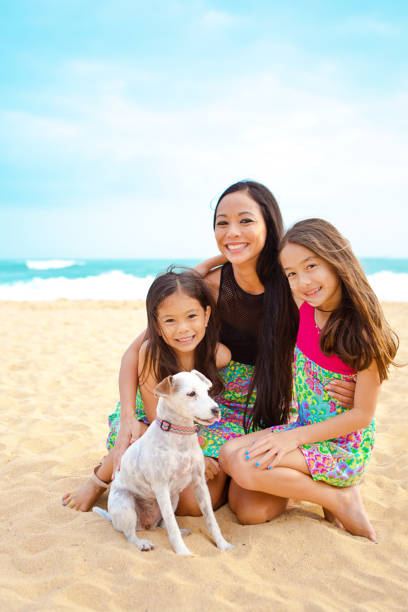 Outdoor Portrait of Hawaiian Mother and Children Group Portrait of a Hawaiian Polynesian family outdoor on the beach. Two young girls with their mother posing, smiling and looking at camera half body group portrait. kauai photos stock pictures, royalty-free photos & images
