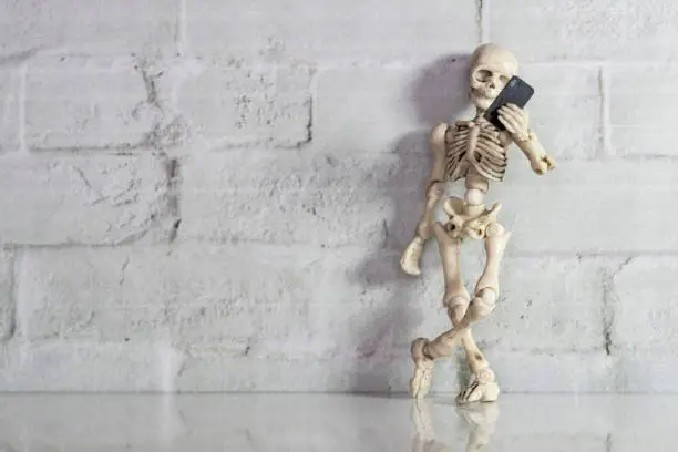 Skeleton standing with a smartphone in his hand