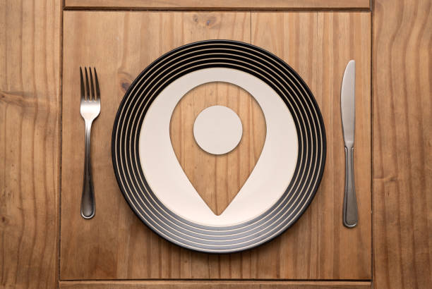 Location mark on plate with fork and knife on rustic wooden table in natural light, top view