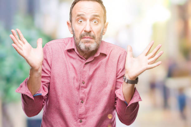 istock Middle age hoary senior man over isolated background clueless and confused expression with arms and hands raised. Doubt concept. 1048927944