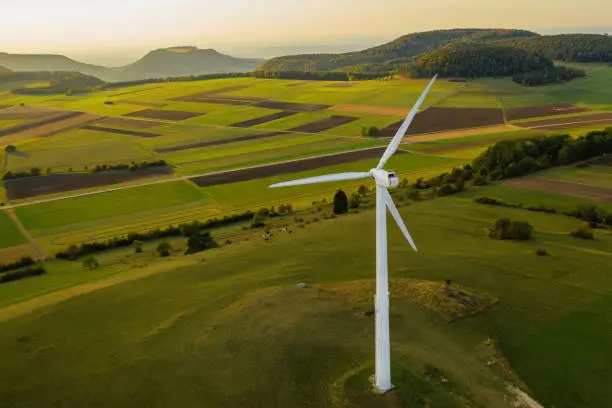 Photo of Alternative Energy Wind Turbine in Beautiful Green Landscape at Sunset