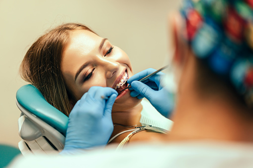 Dentist examine female patient with braces in denal office