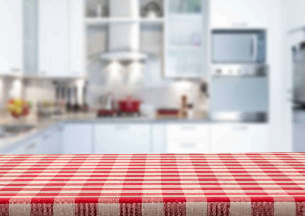 Empty kitchen countertop covered with red and white checkered tablecloth Empty kitchen countertop covered with red and white checkered tablecloth with blurred modern kitchen at background. Predominant colors are white and red. Very suitable for product montage. tablecloth photos stock pictures, royalty-free photos & images