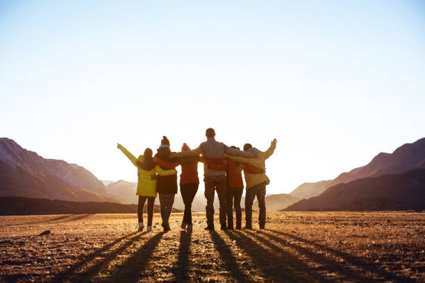 Group of friends against sunset mountains stock photo