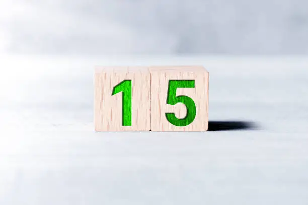 Number 15 Formed By Wooden Blocks On White Table