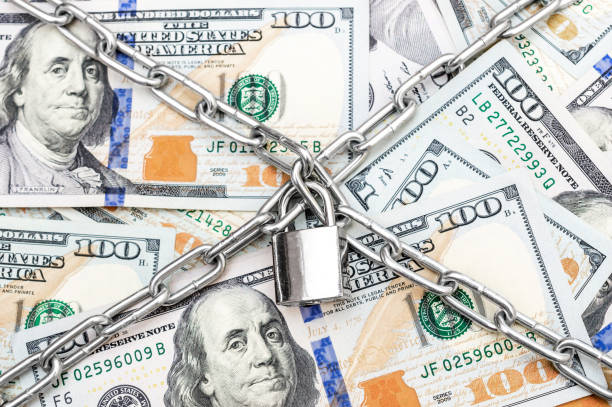 Crossed chain with padlock on the dollar bills. Protection and security money. Crossed chain with padlock on the dollar bills. Protection and security money. american one hundred dollar bill photos stock pictures, royalty-free photos & images