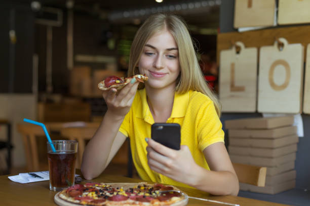 istock Young woman eating a pizza and taking selfie 1048945464