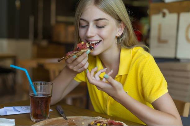 istock Young woman eating pizza at restaurant 1048953184
