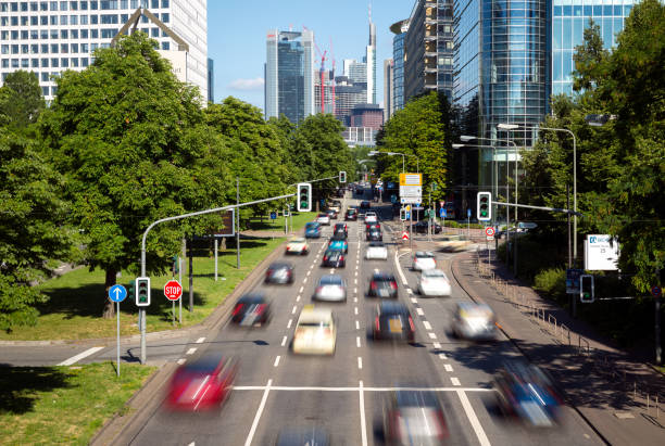 Frankfurt Germany, June 26th 2018, Road traffic on multilane highway with cars, trucks and busses, close to the Frankfurt Trade Fair Area. Skycrapers, modern office buildings, business premises and green zones with trees are located around.