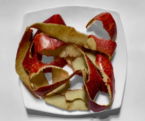 Apple peels in white plate on surface