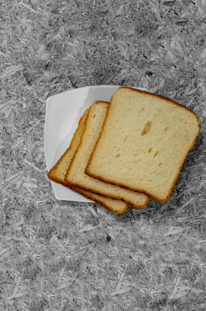 Bread pieces and slices in white plate on rugged surface