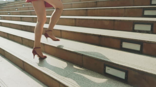 Close up of woman's legs stepping up on stairway in city - Stock video