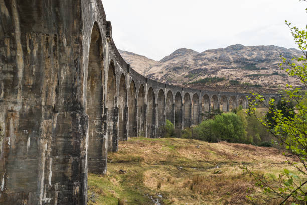 istock Old train railway with arched bridge surrounded by trees with hills in view, Glennfinnan Viaduct, Scottish Highlands. 1048986274
