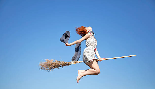 istock Young red-haired witch on broom flying in the sky 104899626
