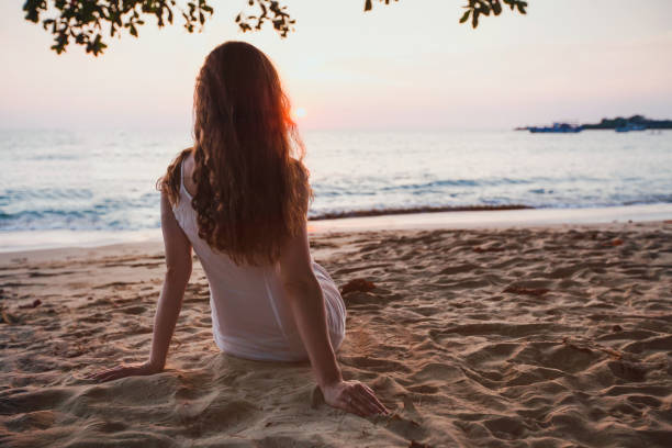istock relaxation, romantic girl sitting on the beach 1049012234