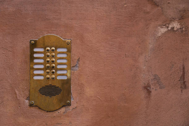 Old bronze intercom on an old wall with peeling paint stock photo