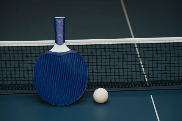 istock Table tennis rackets and ball and net on a blue pingpong table 1049016122