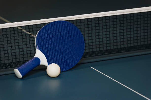 istock Table tennis rackets and ball and net on a blue pingpong table 1049016128