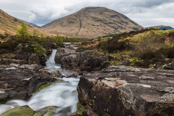 istock Glencoe river with smooth water flow and cloudy day. hill views at the back 1049022434