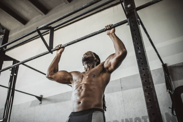Strength and power Determined man doing chin-ups on gym training at gym chin ups photos stock pictures, royalty-free photos & images