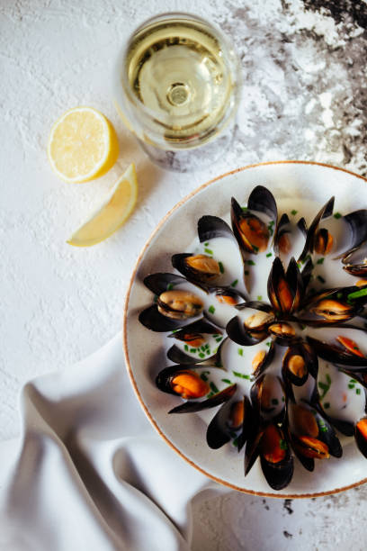 istock Boiled mussels and white wine on white stone table. 1049043178
